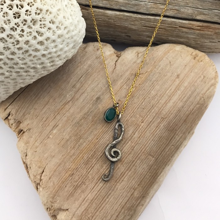 Silver chain with musical treble clef pendant and natural stone.